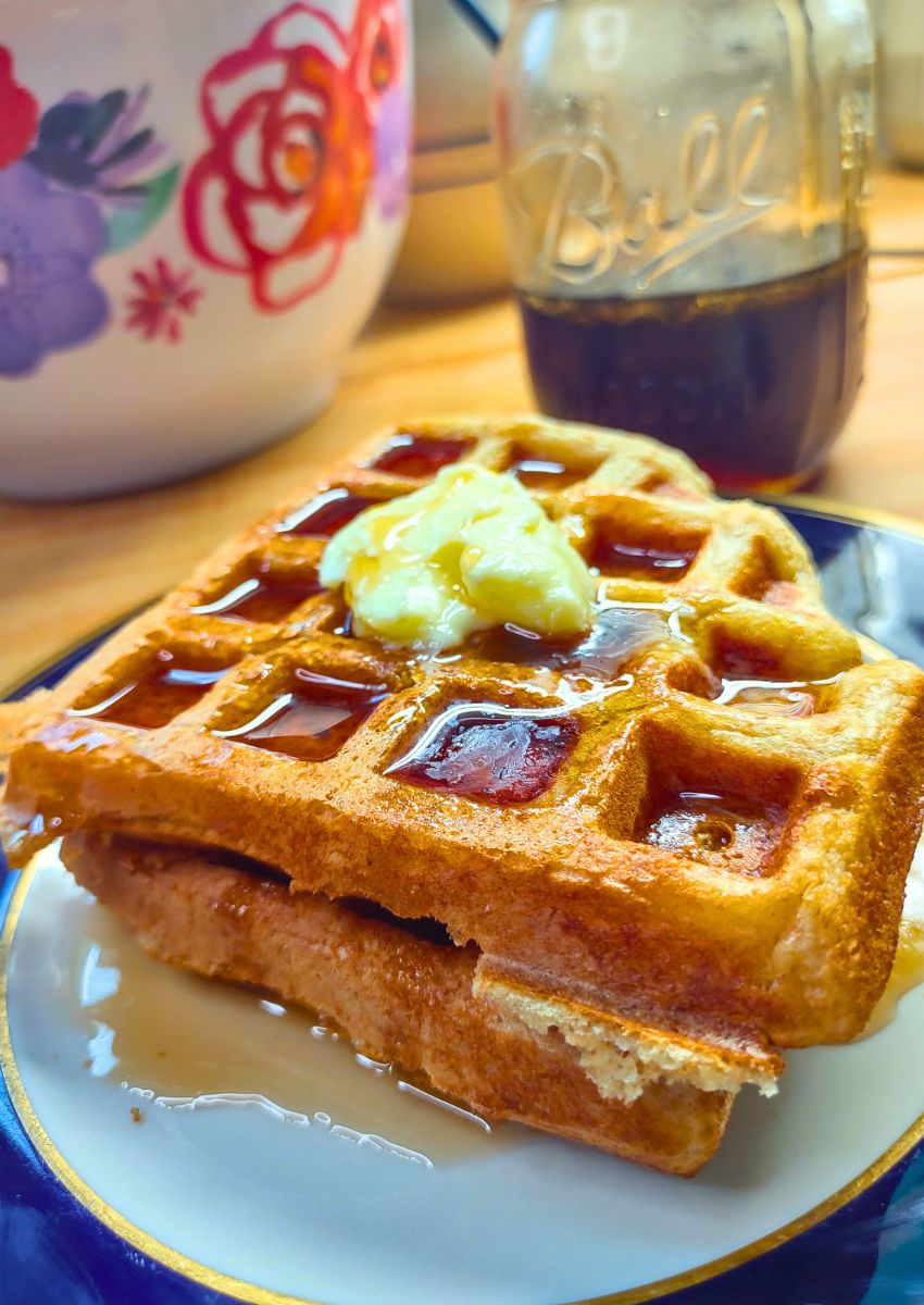overnight sourdough waffles on a plate with butter and maple syrup on it.