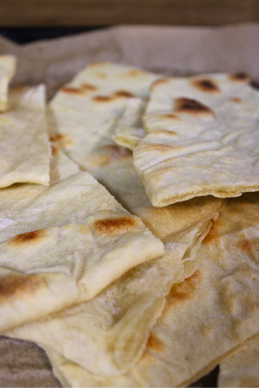 Close-up of homemade Israeli-style matzah stacked on a baking tray, showing crispy thin layers and golden brown spots, easy unleavened bread recipe