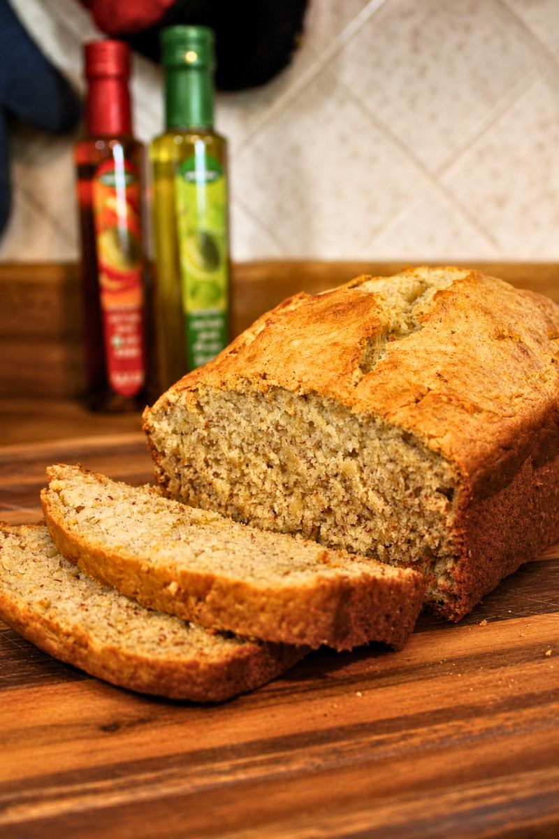 Super moist sourdough banana bread sliced on a wooden cutting board with a golden brown crust and soft texture, easy homemade sourdough discard banana bread recipe from Santa Rosa Homestead.